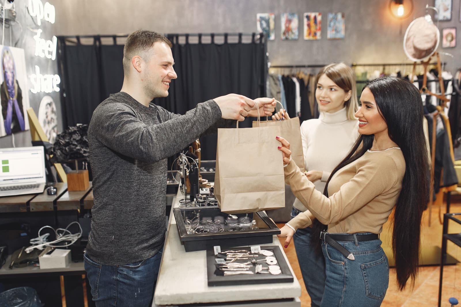 A shop owner handing a bag over the counter to satisfied customers