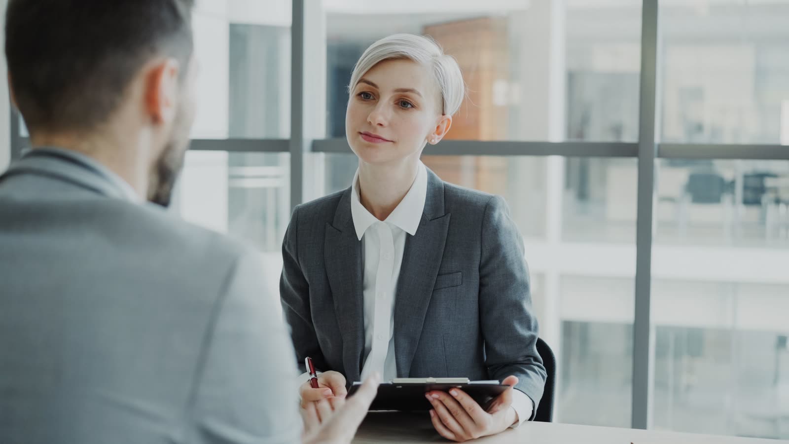 Two professionals collaborating side by side at a desk in a bright office