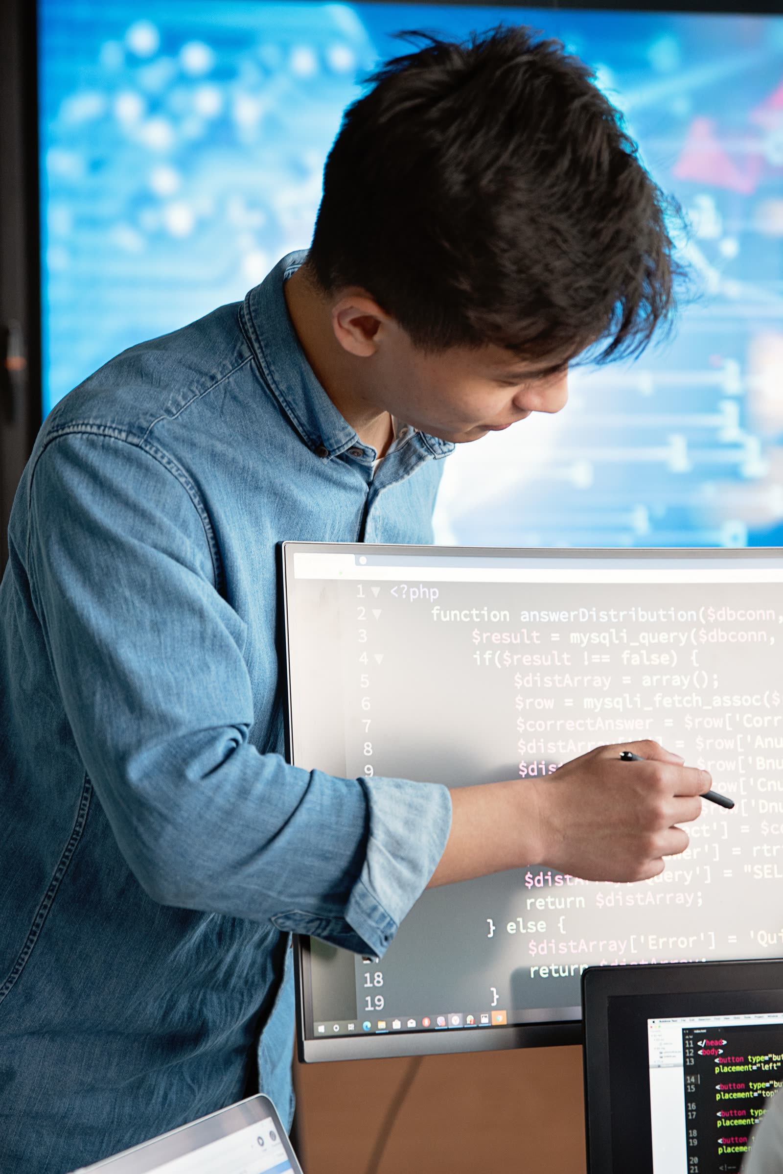 A technical professional pointing at a screen to help a colleague